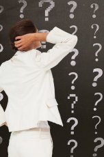 Frau steht vor Tafel mit Fragezeichen