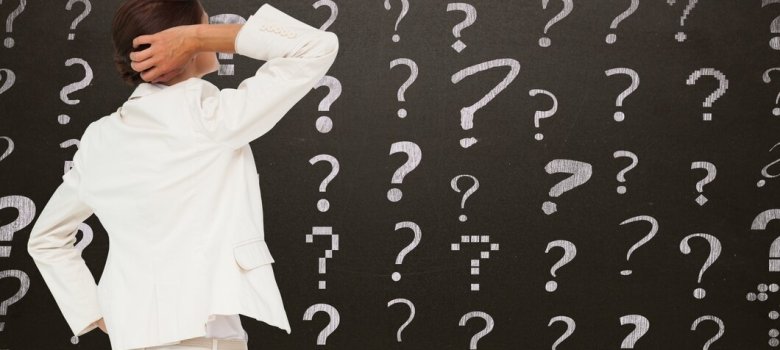 Frau steht vor Tafel mit Fragezeichen